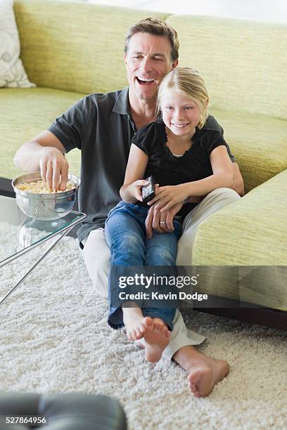 father with daughter (7-9) watching television - girls barefoot in jeans stockfoto's en -beelden