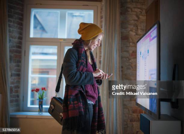 young woman smiling with smartphone in front of monitor - facebook profile stock pictures, royalty-free photos & images