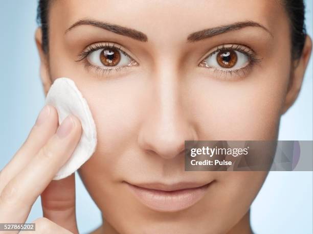 young woman wiping face with cotton pad. - cotton pad stock pictures, royalty-free photos & images