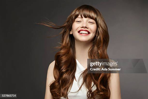 studio shot of smiling young woman - frau beauty welliges haar stock-fotos und bilder