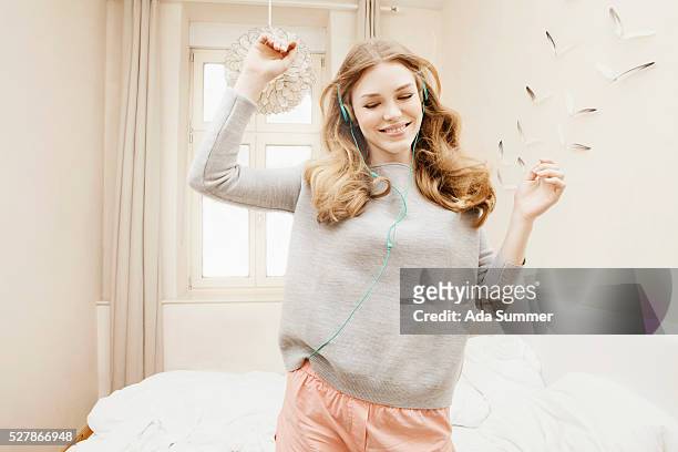 young woman wearing headphones and dancing to music - chica bailando en pijama fotografías e imágenes de stock
