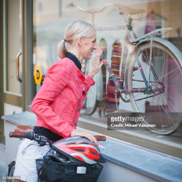 woman looking at bicycle in window display - shopping with bike stock-fotos und bilder