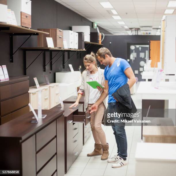 young couple in furniture store - möbelgeschäft stock-fotos und bilder