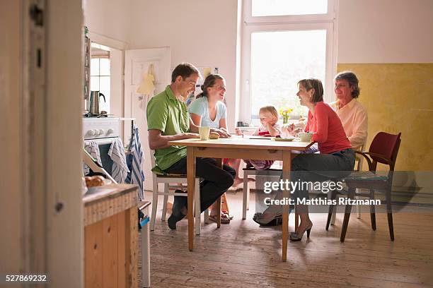 girl (1-2) sitting at table with parents and grandparents - child eat side photos et images de collection