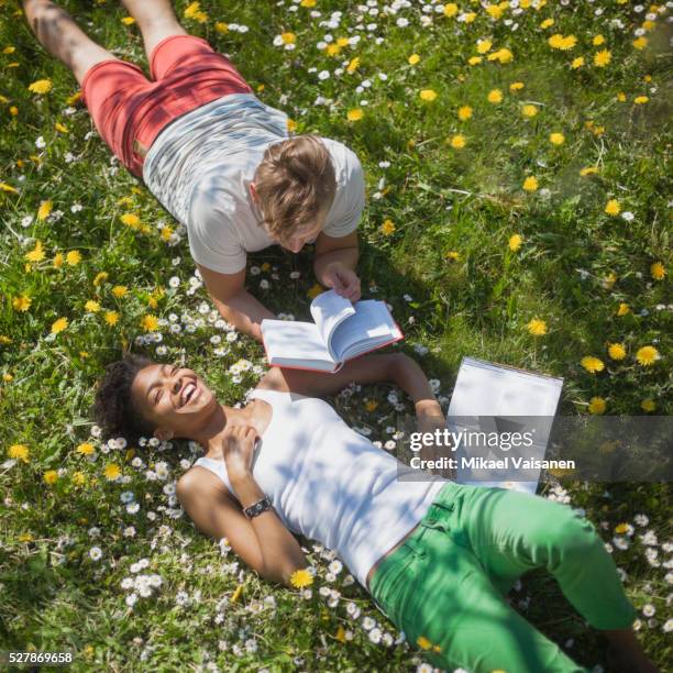 young couple lying in grass with books - romance flowers stock pictures, royalty-free photos & images