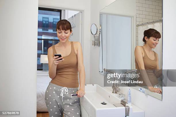 woman text messaging in bathroom - brush teeth phone stock pictures, royalty-free photos & images