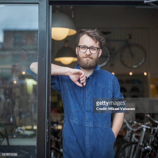 bicycle mechanic standing in bike shop - white jumpsuit stock pictures, royalty-free photos & images