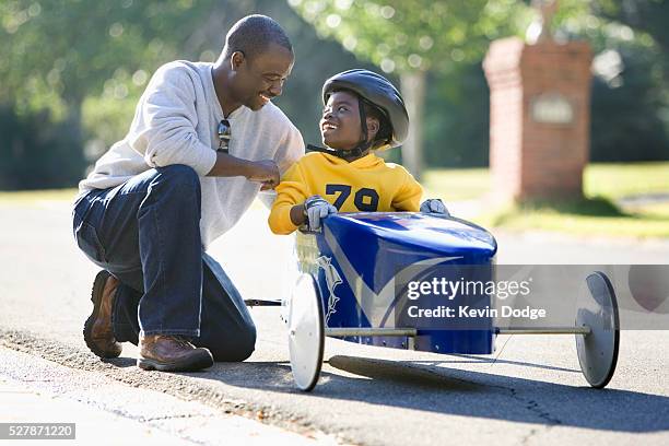 boy sitting in soapbox car talking to father - soapbox cart foto e immagini stock