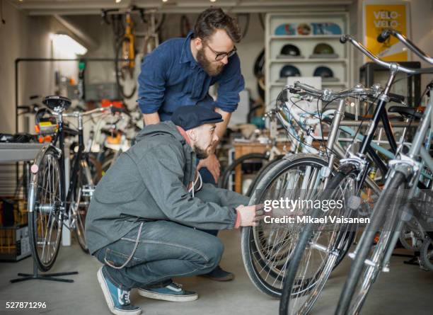 customer with salesperson looking at bicycles in bike shop - buying a bike bildbanksfoton och bilder