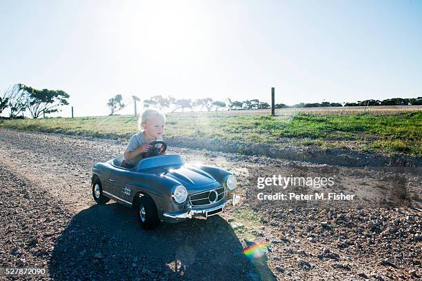 little boy in toy car on country road - modellauto stock-fotos und bilder