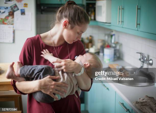 mother embracing son (2-3) in kitchen - mother holding baby stockfoto's en -beelden