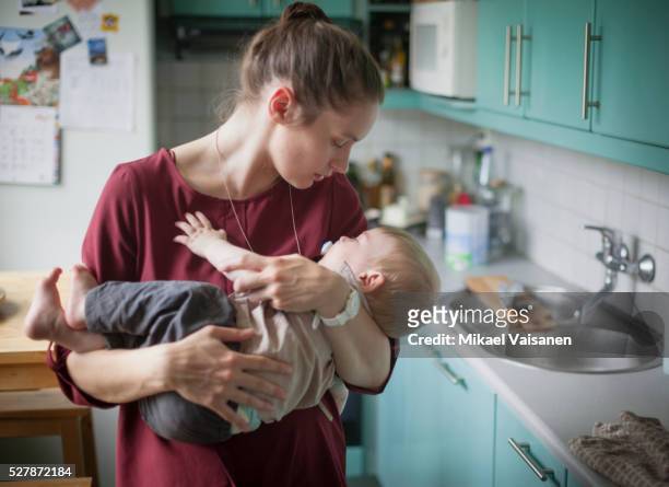 mother embracing son (2-3) in kitchen - baby being held stock pictures, royalty-free photos & images