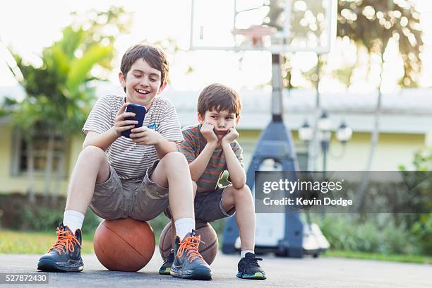 brothers (6-7), (8-9) playing handheld video game - sibling jealousy stock pictures, royalty-free photos & images