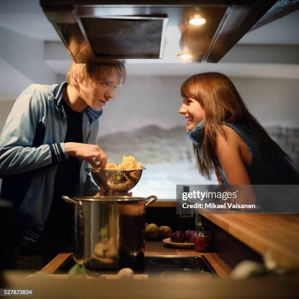 man cooking and talking to woman - couple in kitchen foto e immagini stock