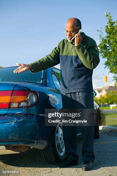 man using a cell phone beside his scratched car - car scratch stock pictures, royalty-free photos & images