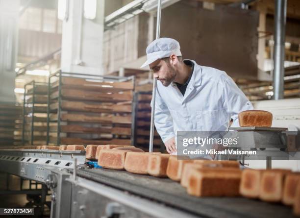 baker on bread production line - nahrungsmittelfabrik stock-fotos und bilder