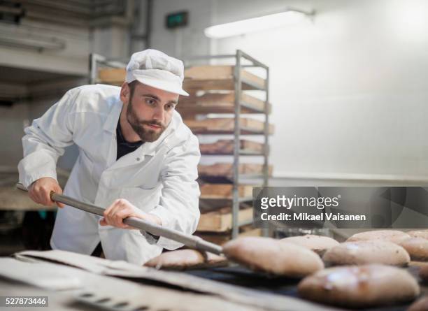 baker on bread production line - pasteleria fotografías e imágenes de stock