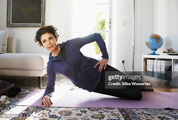 mid-adult woman doing yoga at home - best animated short film stock-fotos und bilder