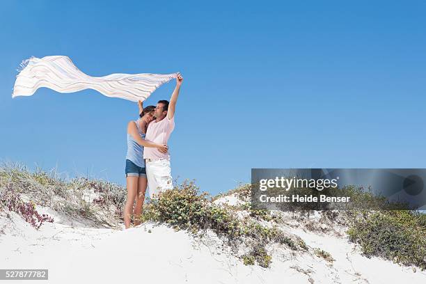 couple holding a windblown beach towel - beach towel stock pictures, royalty-free photos & images