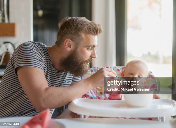 father feeding baby girl (12-23 months) on high chair - father and baby stock pictures, royalty-free photos & images