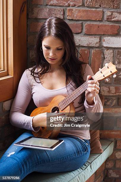 woman learning to play ukulele - ukulele stock-fotos und bilder