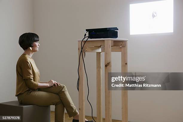 woman watching projection in empty studio - diaprojektor stock-fotos und bilder
