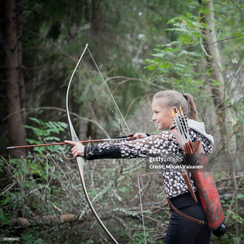 Girl (10-12) shooting with boa and arrow