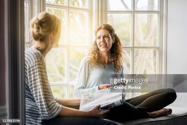 young female friends talking on window sill - sharing coffee stock pictures, royalty-free photos & images