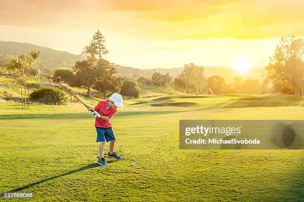 young boy golfer teeing off during sunset - amateur golfer stock pictures, royalty-free photos & images