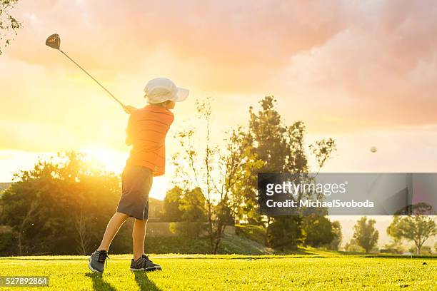 young boy golfer teeing off during sunset - play off stock pictures, royalty-free photos & images