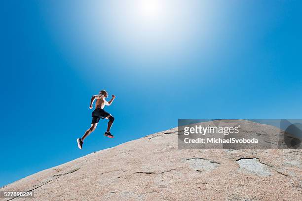 male running up a granite boulder in the mountains - uphill stockfoto's en -beelden