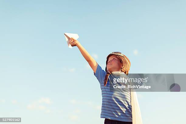 young boy dressed as pilot flies paper airplane - captains day stockfoto's en -beelden