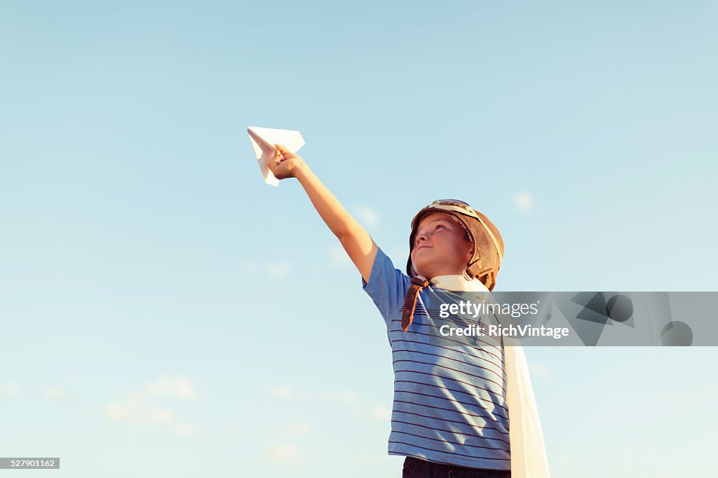 Garoto vestido de piloto de avião voa em papel