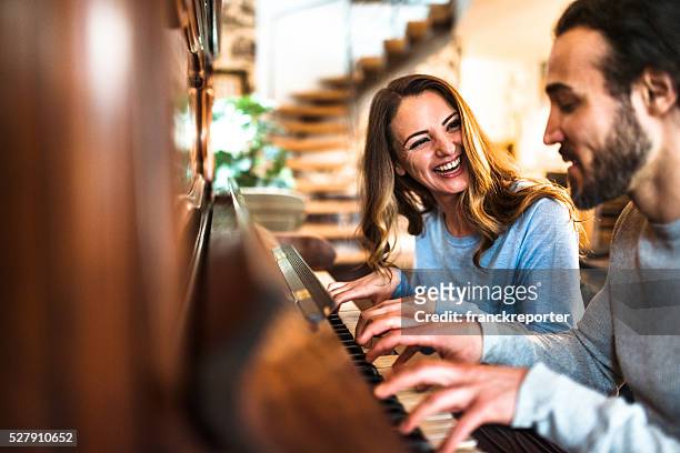 french couple playing the piano in a parisen house - piano stock pictures, royalty-free photos & images