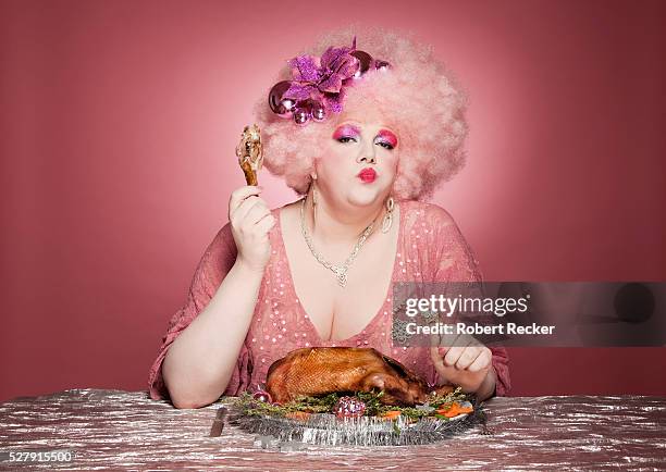 woman with flamboyant hairstyle and outfit in pink with roast goose - sitting at table looking at camera stock-fotos und bilder
