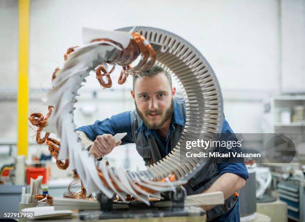 industrial worker in blue overall in electric motor factory - industrial laborer foto e immagini stock