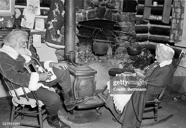 At home with Mr. And Mrs. Claus . The couple who dress as the revered Christmas giftgivers are shown seated at home, him smoking a long pipe and her...