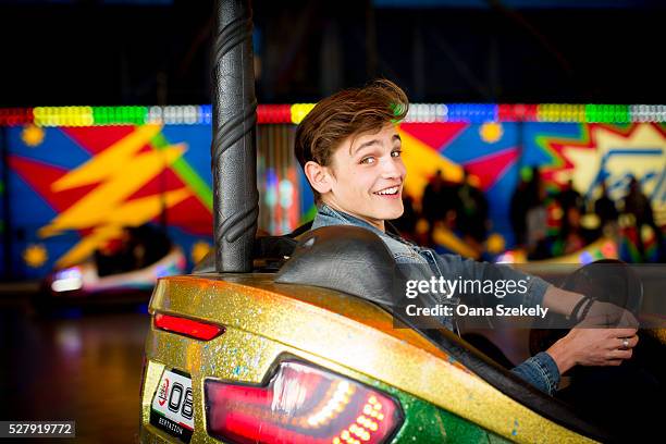 teenage boy driving bumper car in amusement park - autoscooter stock-fotos und bilder