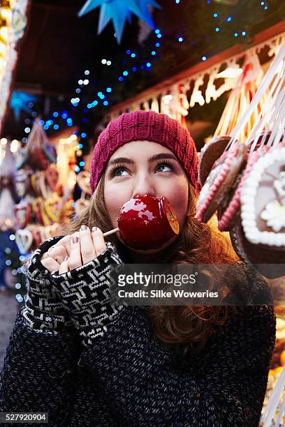 young adult woman having fun on a christmas market - eat apple stock pictures, royalty-free photos & images