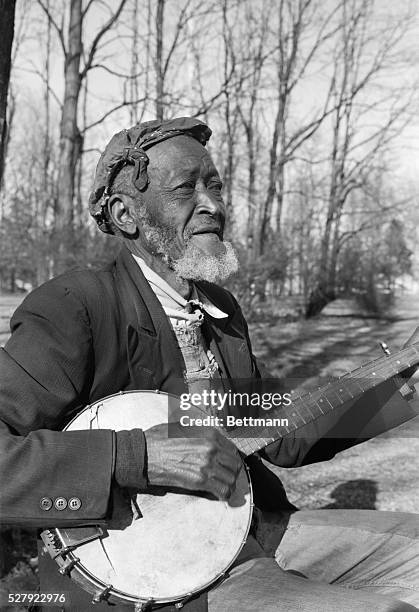 Photo shows an African-American singer playing banjo. Model: L. Reed. Undated.