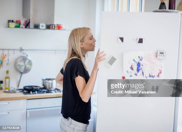 young woman looking into refrigerator - refrigerator stock-fotos und bilder
