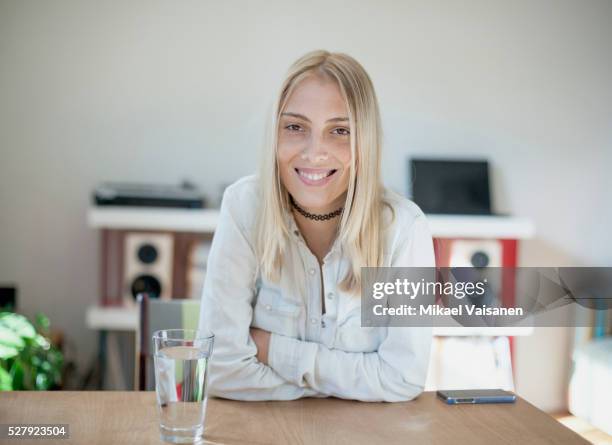 young woman at home - sitting at table looking at camera stock-fotos und bilder