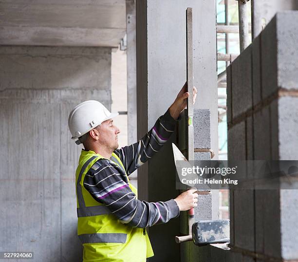 bricklayers checking bricks for level - brick layer stock-fotos und bilder