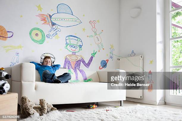 boy (7-9) sitting on sofa - niño en la sala con juguetes fotografías e imágenes de stock