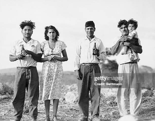 Group of migrant Mexican farm workers by a field in Southern California.