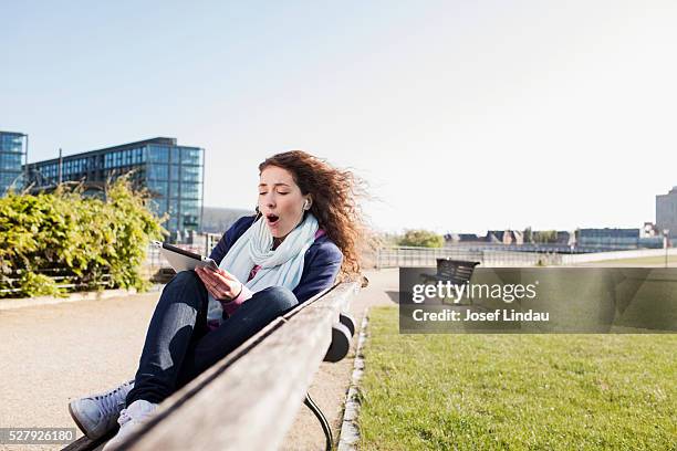 young woman using tablet in park - josef lindau stock-fotos und bilder