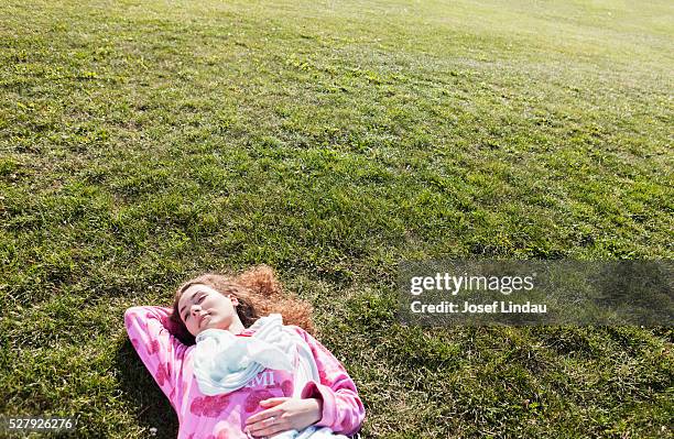 young woman laying on grass - josef lindau stock-fotos und bilder