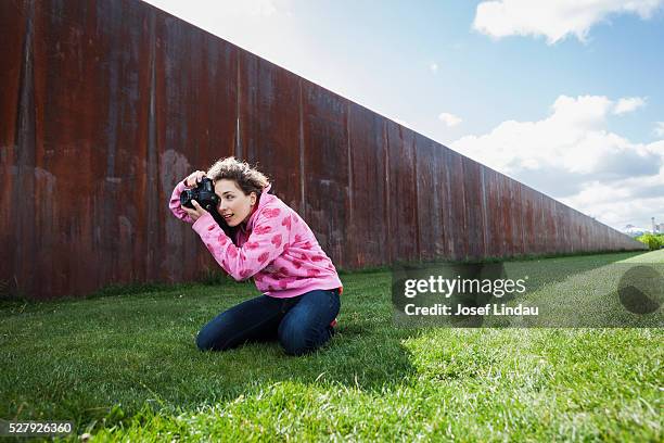 creative woman kneeling to take pictures with digital camera - josef lindau stock-fotos und bilder