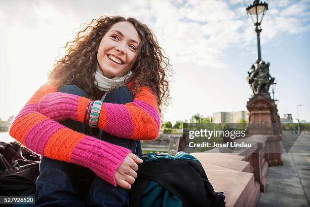 confident woman sitting on a bridge - josef lindau stock-fotos und bilder