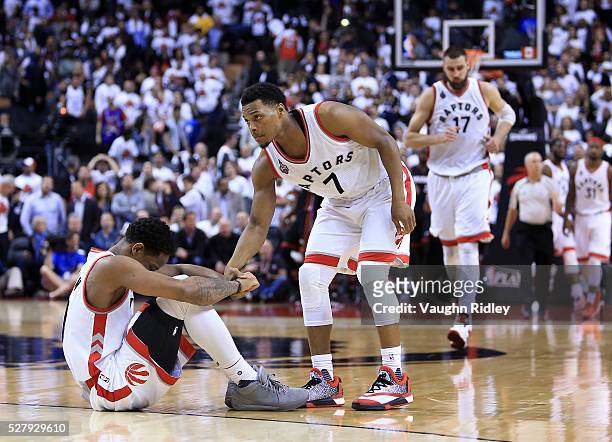 Kyle Lowry of the Toronto Raptors attempts to help DeMar DeRozan up off the floor late in the second half of Game One of the Eastern Conference...